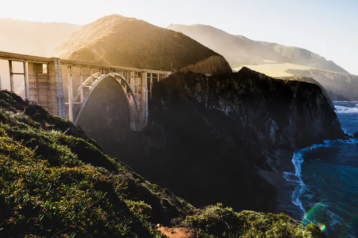 The concrete arch of Bixby Creek Bridge spanning a canyon above the Pacific on California’s Big Sur coast at golden hour